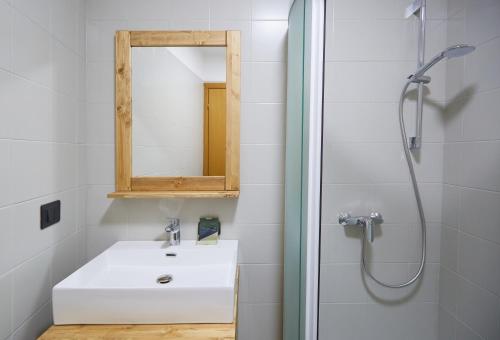 a bathroom with a white sink and a mirror at Villa Alpina Hotel in Forni di Sopra