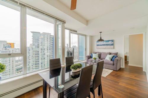 a living room with a table and chairs and windows at Home in the Sky with Gorgeous Water Views in Vancouver