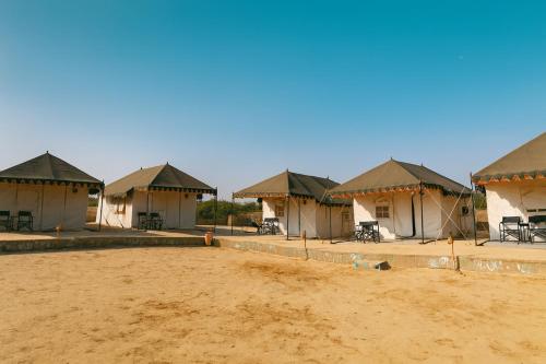 a group of houses under construction in the desert at Stayguru Patgar Tent in Dhordo