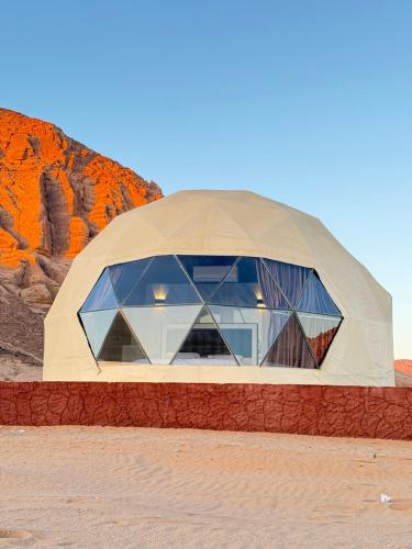 une maison en forme de dôme avec des fenêtres en verre dans le désert dans l'établissement Wadi Rum CAMP, à Disah
