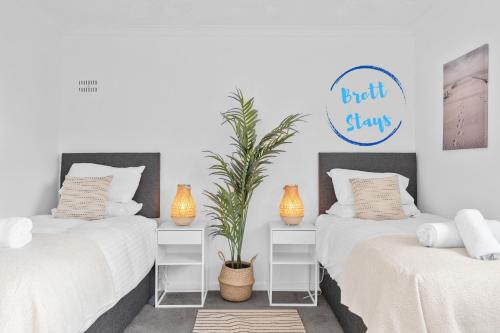 two beds with white sheets and a potted plant at Contractor Accommodation 4 Bedroom House Sleeps 7 Free Van Parking Near Avonmouth Docks in Avonmouth
