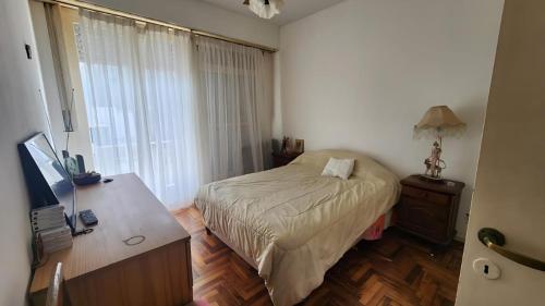 a bedroom with a bed and a desk and a television at Muy Buen Departamento con vista al Mar desde el Balcon Dos Dormitorios a dos Cuadras del Mar sobre Avenida Colon in Mar del Plata
