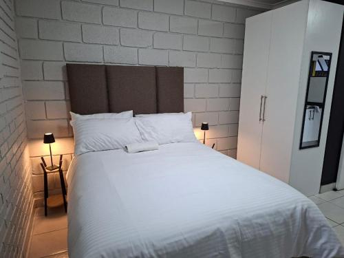 a bedroom with a white bed and a brick wall at Grace Villas 31 in East London