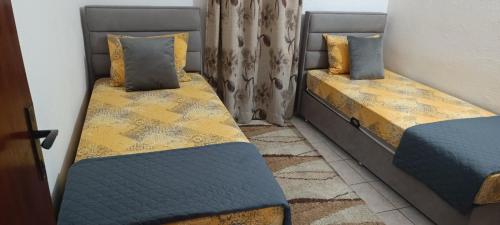 two twin beds in a room with a window at Apartman V,P in Sutomore