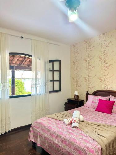 a bedroom with a bed with pink sheets and a window at Cantinho do Céu - Miguel Pereira in Miguel Pereira