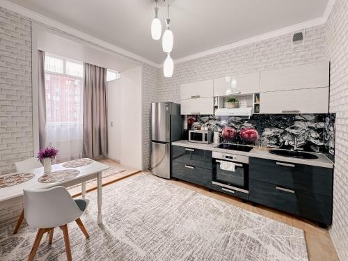 a kitchen with a table and a refrigerator at Евродвушка в ЖК Ирина in Pavlodar