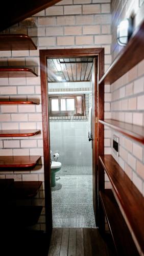 a bathroom with a toilet and a hallway with a door at Pousada Minha Rosa Paixão - PRAIA DO ROSA, SC in Imbituba