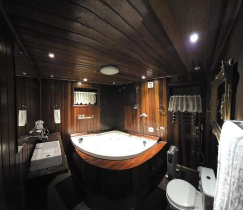 a large bathroom with a tub and a toilet at Chalét com jacuzzi sauna lareira e telao cinema in Campos do Jordão
