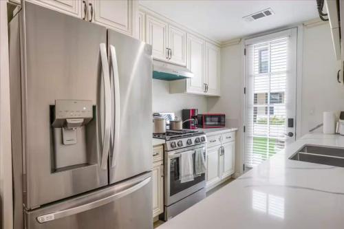 a white kitchen with a stainless steel refrigerator at Newly Built Pasadena Retreat Parking Great Location in East Pasadena