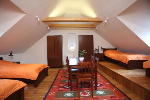 a attic room with two beds and a table and chairs at Csodarabbik Útja Fogadó in Mád