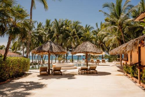 a resort patio with chairs and umbrellas and the ocean at Puertas Paraíso Hotel boutique in Zihuatanejo