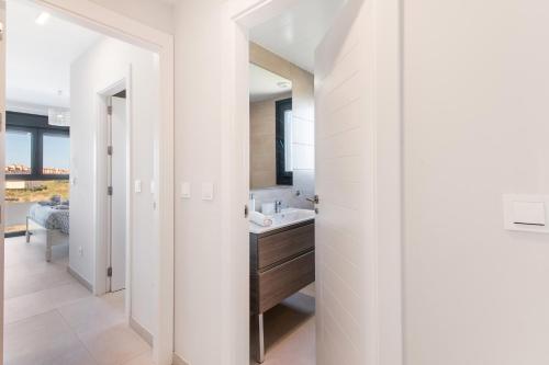Un baño blanco con lavabo y espejo. en Los Flamencos, en Isla Canela
