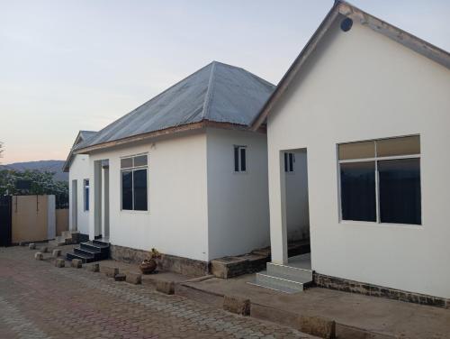 een wit huis met een grijs dak bij P plus lodge in Iringa