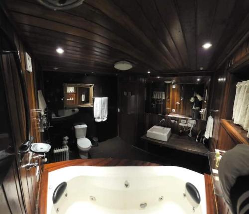 a large bathroom with a tub and a toilet at Chalét com jacuzzi sauna lareira e telao cinema in Campos do Jordão