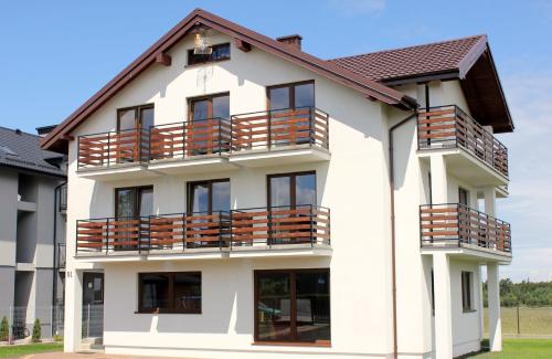 a white building with balconies on it at Komfort i spokój blisko natury - Apartamenty i pokoje ARKO in Ostrowo