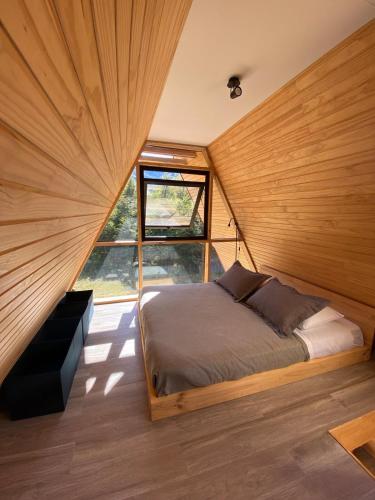 Un dormitorio con una cama en una habitación con ventana. en Incredible Cerro Castillo Shelter, en Villa Cerro Castillo
