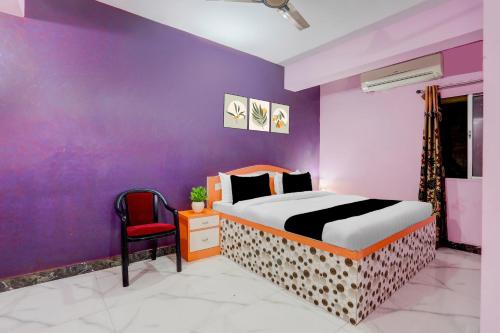 Un dormitorio con una cama y una pared morada. en Hotel O The Triotel Inn, en Dhanbād