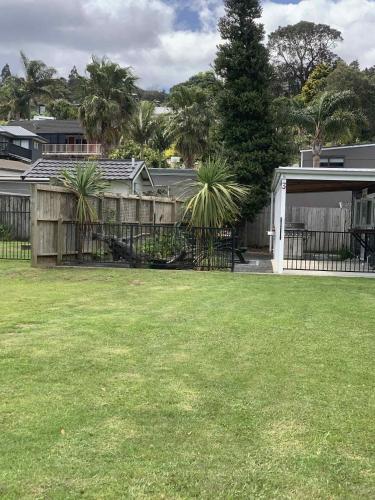 une cour avec une clôture et quelques palmiers dans l'établissement Hosts on the Coast Pawprint Cabins, à Whitianga