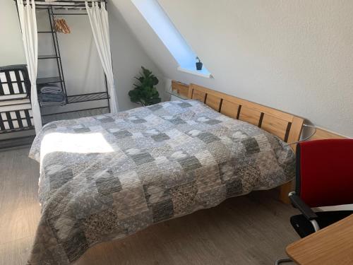 a bedroom with a bed and a red chair at Über den Dächern der Stadt in Bremervörde