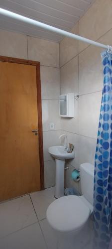 a bathroom with a sink and a toilet and a door at Kitinet completa com varanda Praia de Caiobá in Matinhos