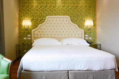 a bedroom with a large white bed with green wallpaper at Hotel Santa Chiara in Venice
