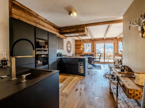 une cuisine avec des armoires noires et un salon dans l'établissement Appartement de prestige spacieux et lumineux avec sauna et parking inclus - FR-1-598-48, aux Gets