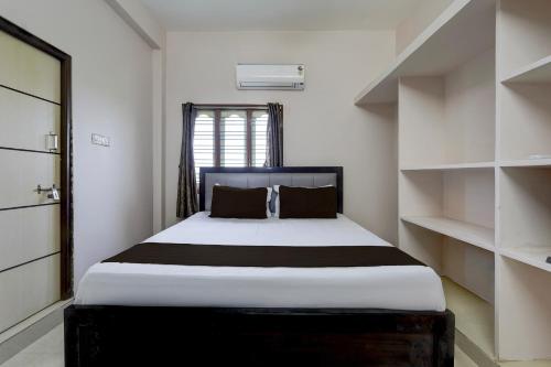 a bedroom with a large bed and shelves at Hotel O V Stayinn in Renigunta