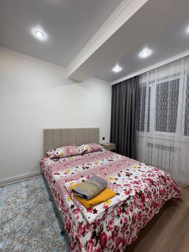 ein Schlafzimmer mit einem Bett mit einer roten geblümten Tagesdecke in der Unterkunft Sunny Home Apartment in Almaty