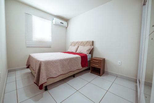 a small bedroom with a bed and a window at Apartamento com garagem a 200m da Praia do Bessa in Tambaú