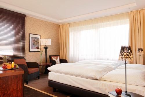 a bedroom with a bed and a chair and a window at Romantik Hotel Waldschlösschen in Schleswig