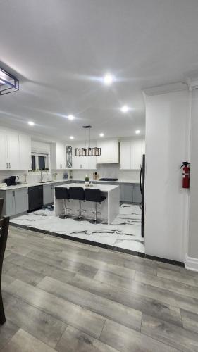 a large kitchen with white cabinets and black appliances at Toronto Guest House in Toronto