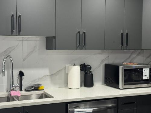 a kitchen with a sink and a microwave at Modern comfort just 20 minutes from the airport, with a full kitchen in Edmonton