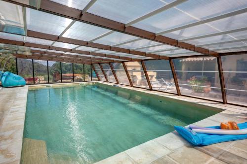 an indoor swimming pool with an open ceiling at Les Gargoulettes in Lauris
