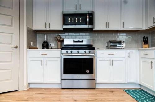オースティンにあるTesla Luxe Retreat Sleeps 10の白いキャビネットとコンロ付きオーブンを備えたキッチン