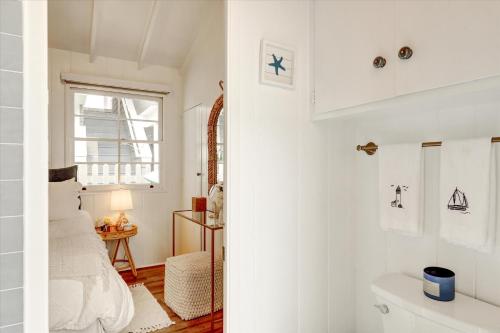 ein weißes Schlafzimmer mit einem Bett und einem Fenster in der Unterkunft Balboa Island Beach Cottage in Newport Beach