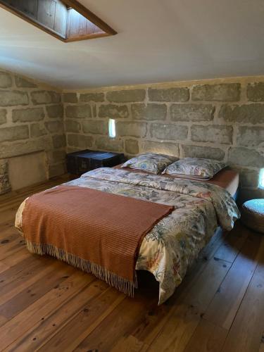 un dormitorio con una cama con una pared de piedra en La malle bleue, en Vallabrix