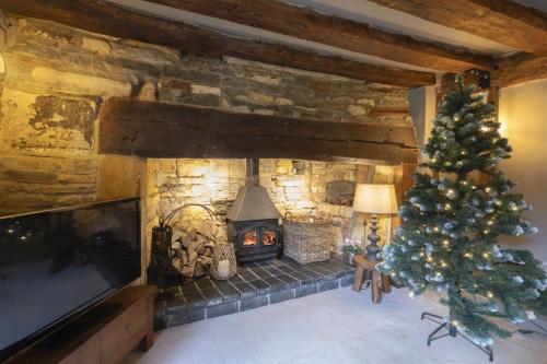 a living room with a christmas tree and a fireplace at Idyllic Cotswold Cottage Near Broadway in Badsey