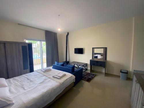 a bedroom with a large bed and a blue couch at Chalet 101 - Zresidence - Faitroun in Al ‘Aqabah