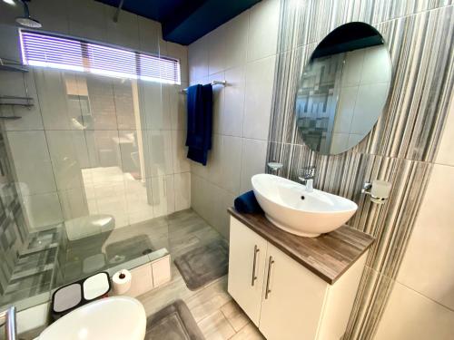 a bathroom with a sink and a mirror at Modern Van Riebeeck Park Accomodation in Worcester