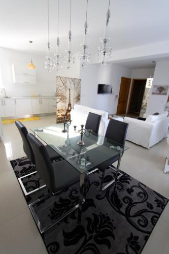 a dining room with a glass table and black chairs at Marble Arch in St Julian's
