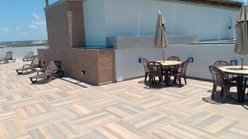 a patio with tables and chairs and an umbrella at Ap Praia do Frances in Marechal Deodoro