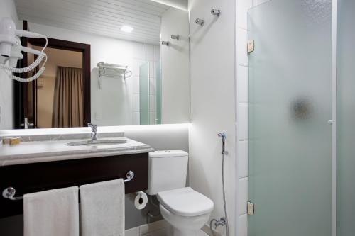 a bathroom with a toilet and a sink and a shower at Mercure Jaragua do Sul in Jaraguá do Sul