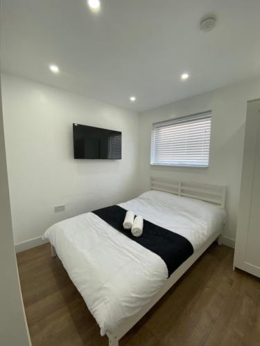 a bedroom with a bed with a tv on the wall at Modern en-suite rooms Luton air port in Luton