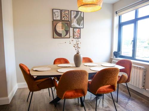a dining room table with chairs and a vase on it at Riverside Dingle - Luxury Apt 4 in Dingle