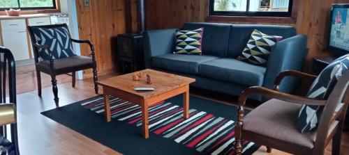 a living room with a blue couch and a coffee table at Cabaña en el campo in Puyehue