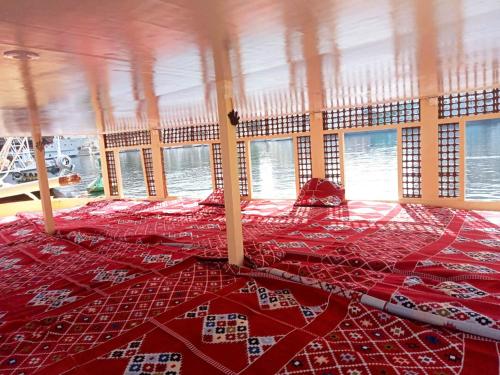 a bed with a red comforter in a room with windows at Katadool Boat in Aswan