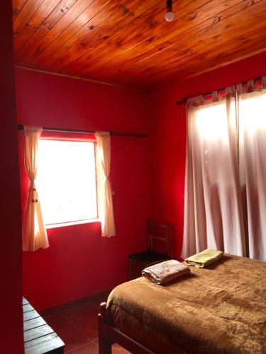 a bedroom with red walls and a bed and a window at Casa privada en Maimara in Maimará