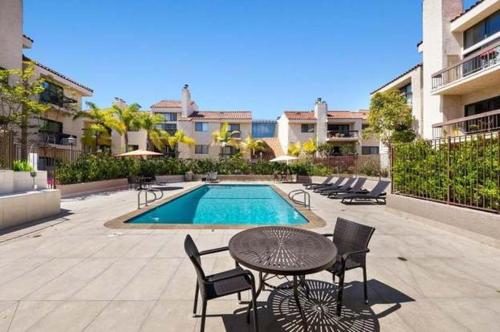a patio with a table and chairs and a pool at Venice Beach Lux Retreat Coastal Apartment Haven in Los Angeles