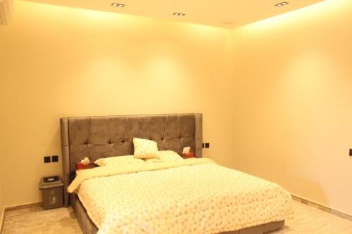 1 dormitorio con 1 cama con cabecero gris en فيلا راقية وسط المدينة, en Az Zulfi