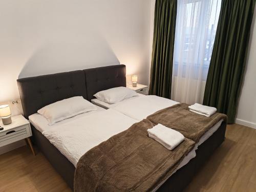a bedroom with a large bed with two towels on it at Terra Ștrand Residence Ștei in Ştei